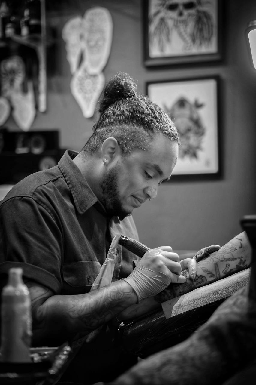 Tattoo artist working on a client's arm in a tattoo parlor.
